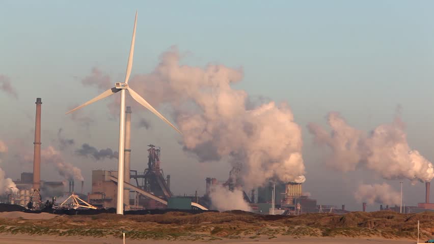 Wind turbine with big smokestacks in the background