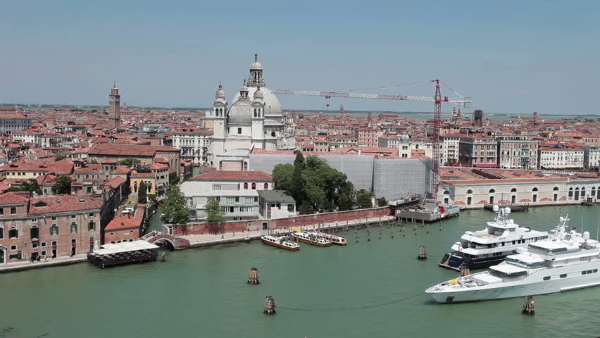 Venice Italy canal and lagoon passing by the Santa Maria delle Salute basilica cathedral. Large wealthy luxury yachts moored in the middle of water while on their adventure and vacation to Venice. 