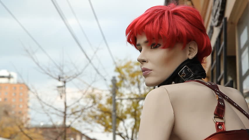 Street mannequin. A mannequin on the sidewalk outside a sex shop. Red hair. Shallow depth of field. 