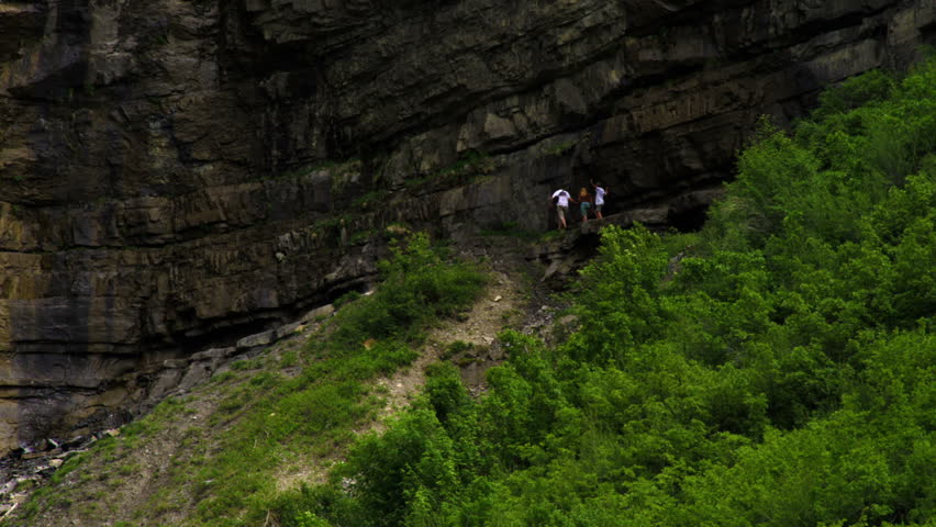 Three people walking along the base of a cliff near Bridal Veil Falls in Provo Canyon, Utah.