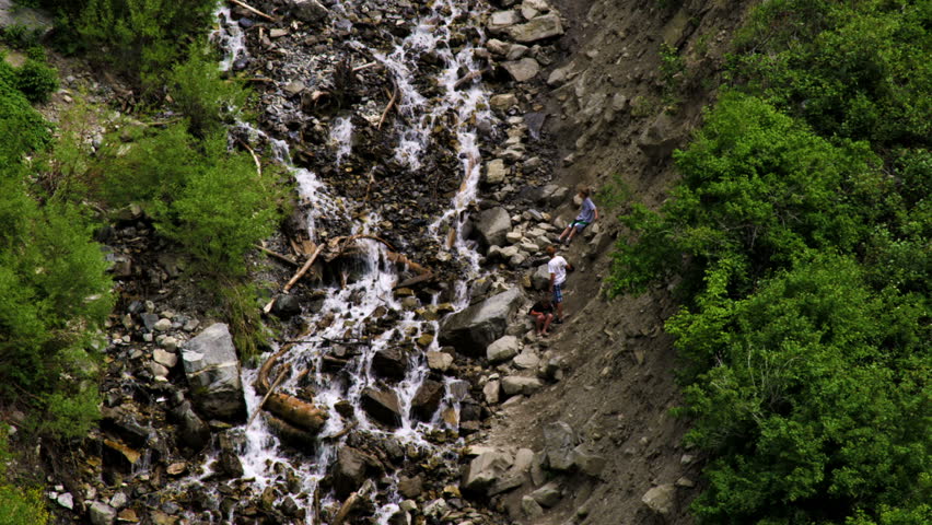 Three youth climbing up the rocks near the stream that flows from Bridal Veil Falls in Provo Canyon, Utah.