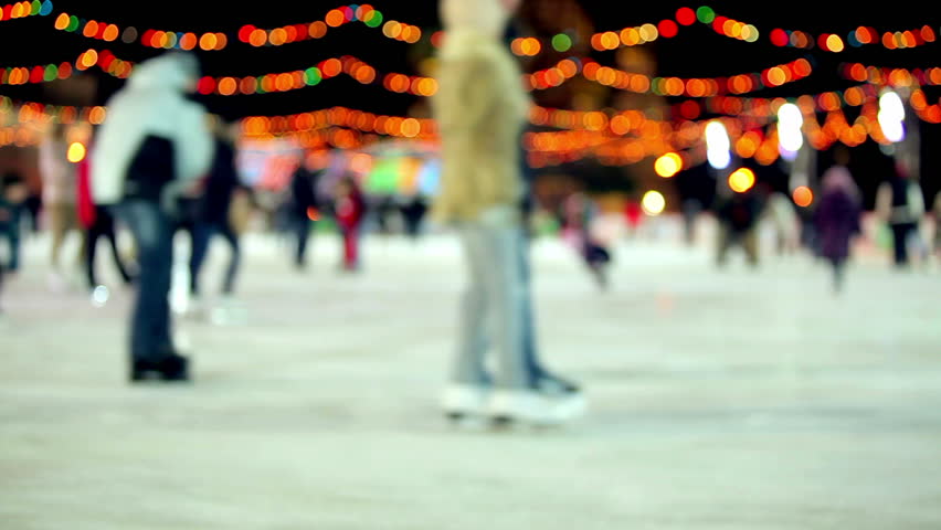 Winter outdoor ice skating with Christmas lights & crowds of people at night