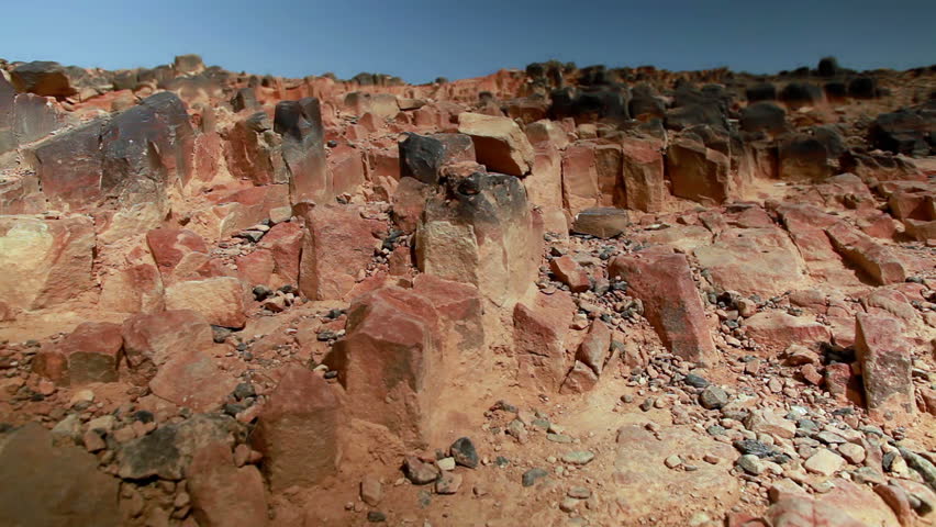 Low angled slide dolly move right to left of the rocky hillside of Ha-Minsara (The Carpentry Shop), a geological formation in the Mitzpe Ramon Crater in Israel.  