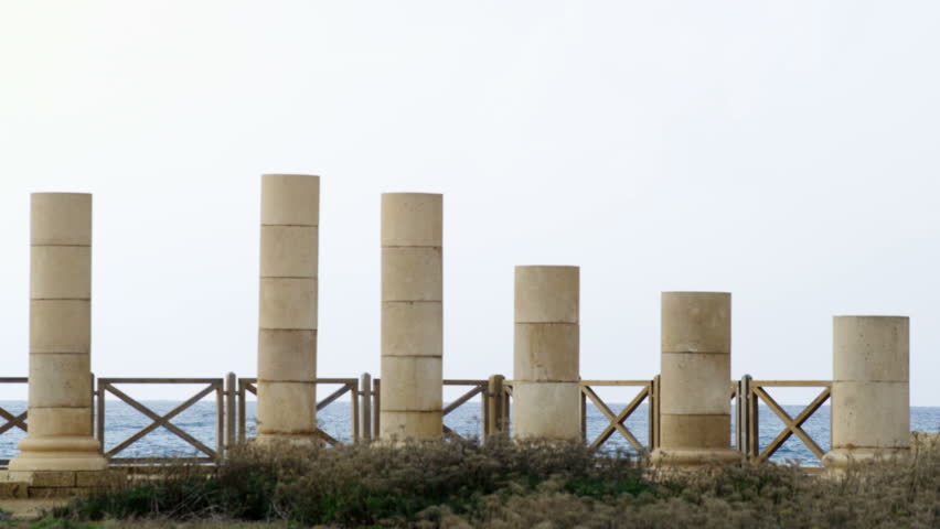 Columns of the palace ruins in Caesarea Israel, in front of a fence barrier and the Mediterranean Sea in the background.  02/28/2011.