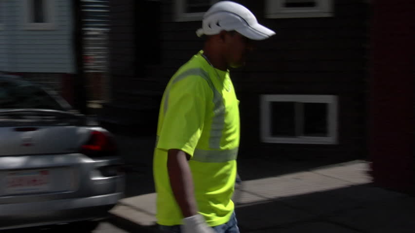 Garbageman grabs scraps of wood from trash pile and tosses them in back of garbage truck