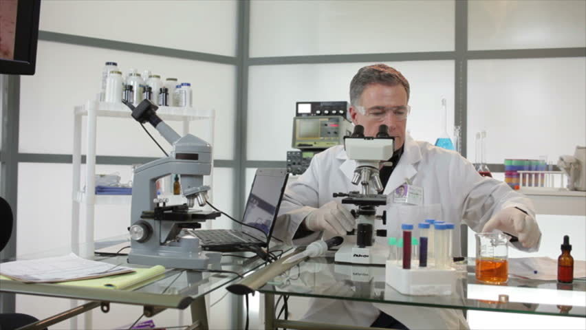 A woman and man who appear to be scientists or chemists working in a laboratory using microscopes and other technologies.