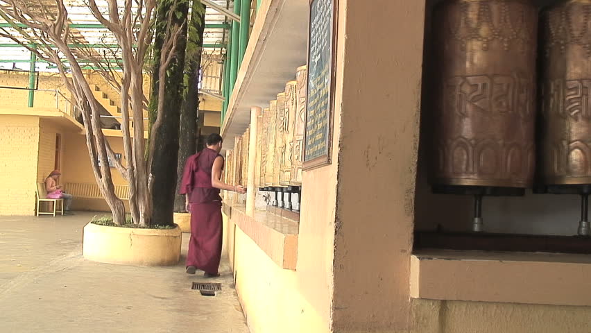 MCLEOD GANJ, INDIA - AUGUST 24, 2006: A Tibetan monk spinning prayer wheels