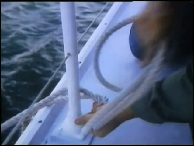 Hands tying rope to railing on ship