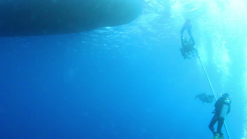 Scuba divers hanging waiting on decoline, completing a saftey stop.