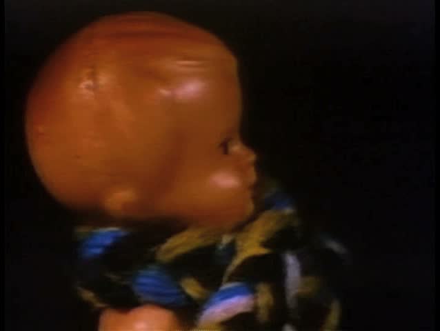Close-up of doll wearing wool scarf slowly turning forward