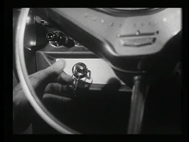 Close-up of hand turning ignition key in 1960s car