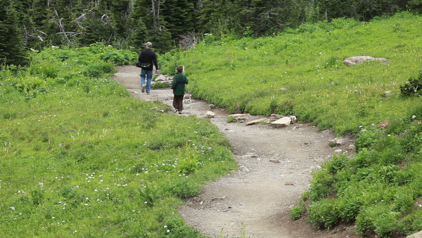 Father and son hike mountain trail for exercise and to explore looking for wildlife in Montana. Family activities important for growth of a happy family.