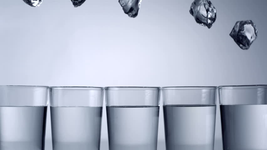 Slo-motion ice cubes falling into row of glasses