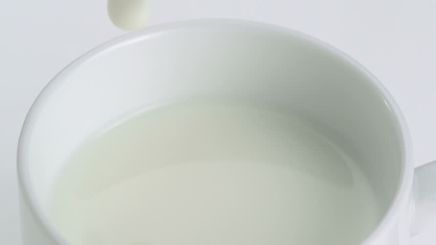 Close-up milk being poured into a white mug