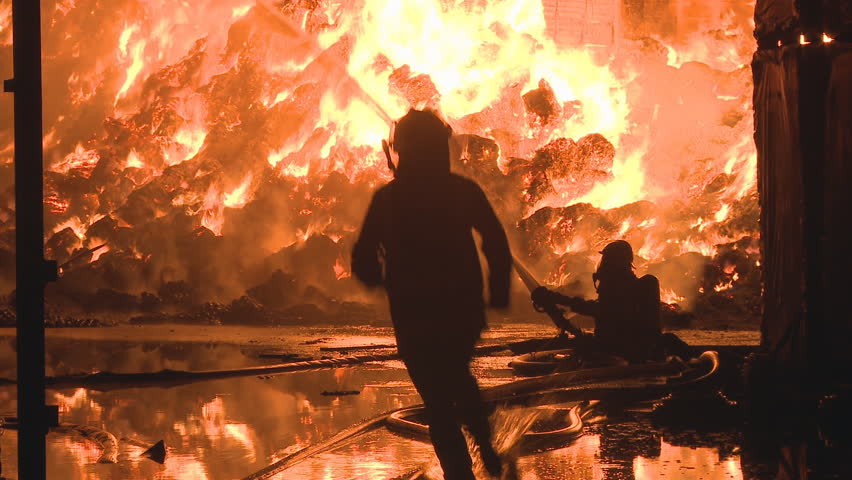 Industrial fire and fireman trying to bring it under control