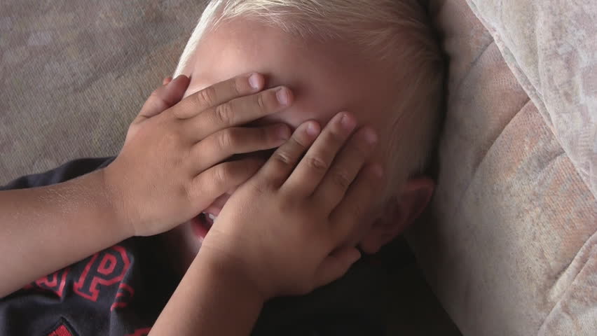 2 year old boy covers face with hands, close-up
