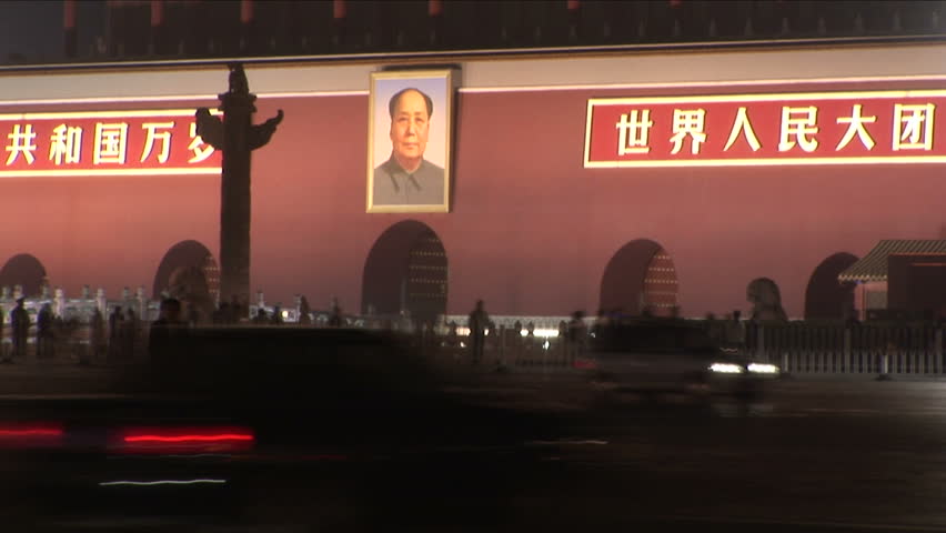 Portrait of Chairman Mao Zedong outside Forbidden City at night with busy traffic driving past in Beijing, China, slow shutter speed