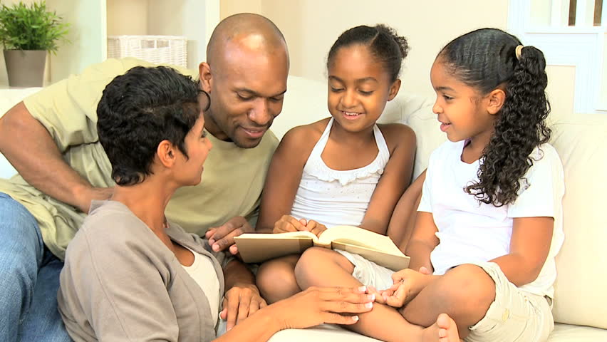 Proud ethnic parents sharing a book with their daughters