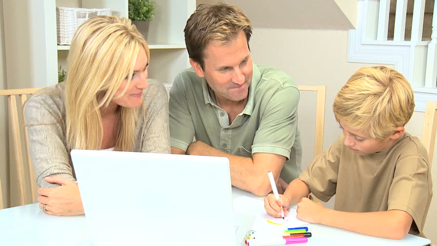 Proud parents watching son using laptop and crayons