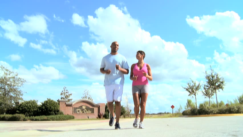 Young ethnic couple keeping to a fitness program together jogging outdoors