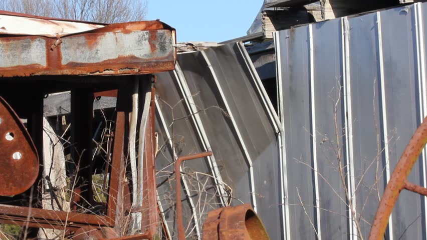 Scrap Metal Pile And Flopping Section Of Tin Building On Windy Day