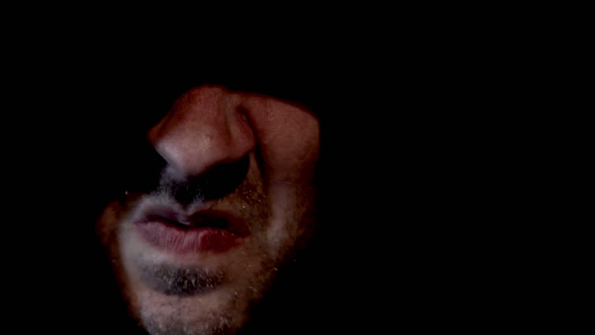 Scary hooded man appearing from darkness screaming
