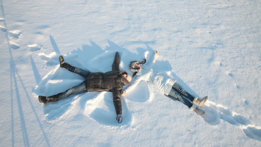 Young couple lying on snow and making snow angels