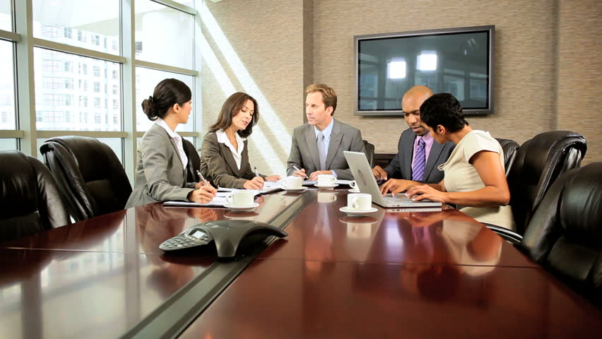 Team of five multi ethnic business people in city clothes meeting in a modern office boardroom