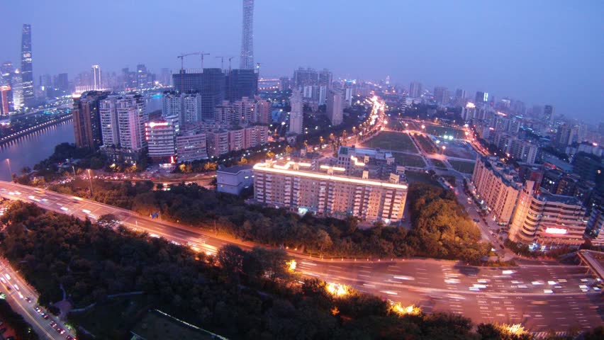 Cars go on road near to Construction Guangzhou New TV Broadcasting Office Building in night, time lapse