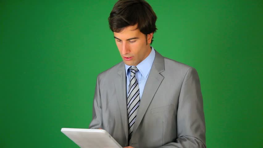 Businessman standing on green background with tablet