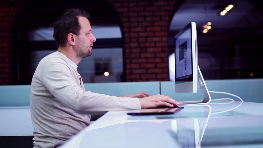 Young man surfing the net on computer in modern interior