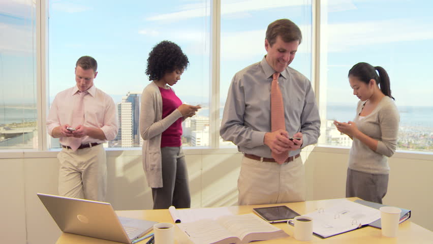 Business associates in office texting on cell phones
