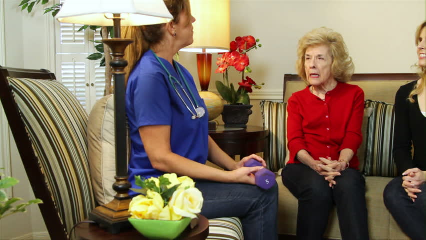 A pretty home health care nurse showing an elderly patient how to use a hand weight to help build strength.