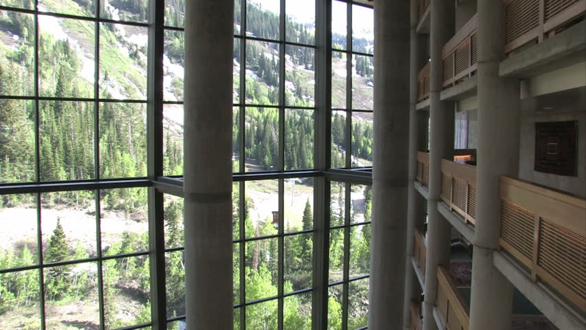 Balconies resort lobby looking down. Large columns, restaurant tables and expansive glass windows open to mountains. Pan left. Wasatch Mountains Salt Lake City, Utah. Luxury hotel, timeshare resort.