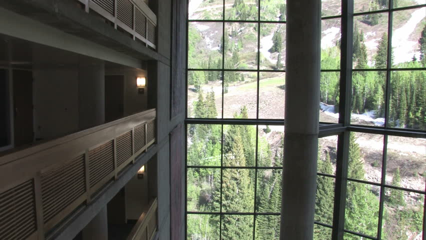 Balconies resort lobby looking down. Large columns, restaurant tables and expansive glass windows open to mountains. Pan left. Wasatch Mountains Salt Lake City, Utah. Luxury hotel, timeshare resort.