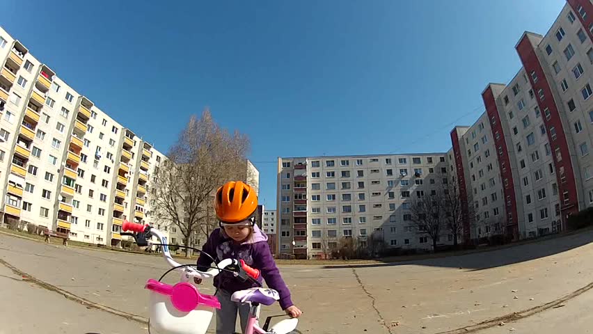 Baby girl in helmet learning to ride on bike 