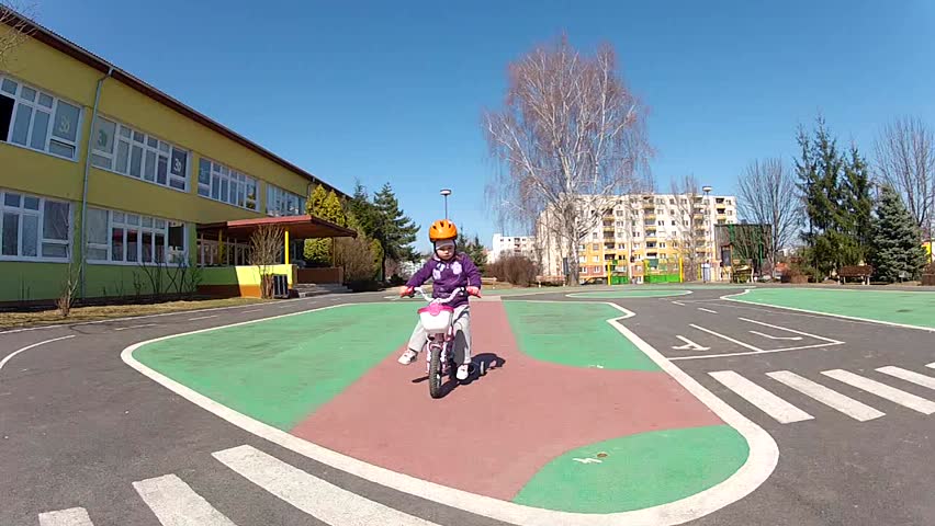 Baby girl in helmet learning to ride on bike 