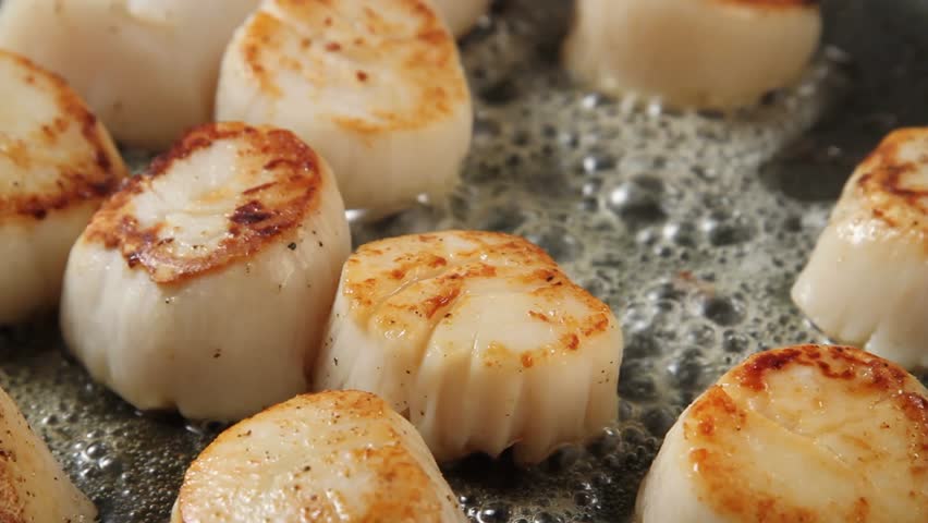Scallops being fried in a pan