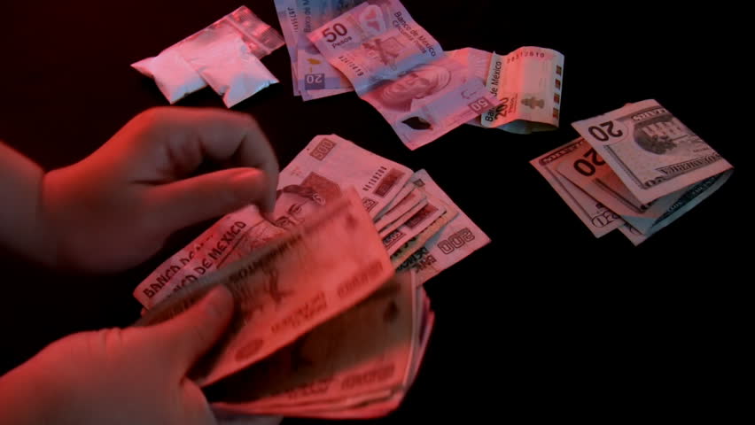 Counting Drug Money (HD). Mexican money from drugs counted on a dark surface. Shot with studio lights and colored gels for visual ambiance.