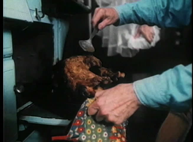 Man basting turkey in oven