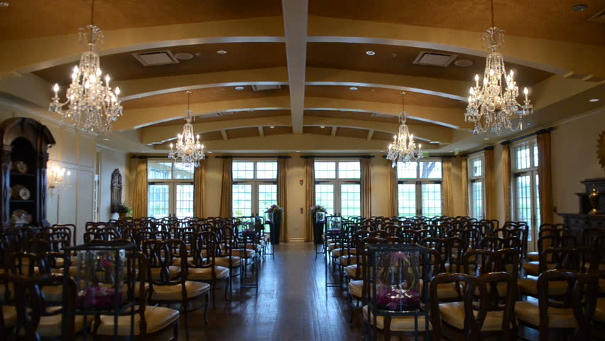 Classy and elegant wedding ceremony setup indoors with rows of empty chairs and gorgeous chandeliers