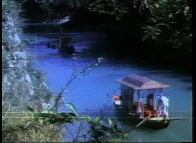 Wide shot of man rowing houseboat in river