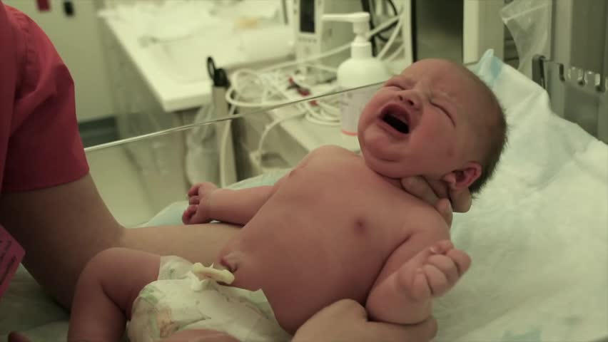 A newborn baby at the hospital being picked up by the nursing staff.