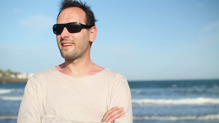 Happy man in sunglasses by the sea looking to camera
