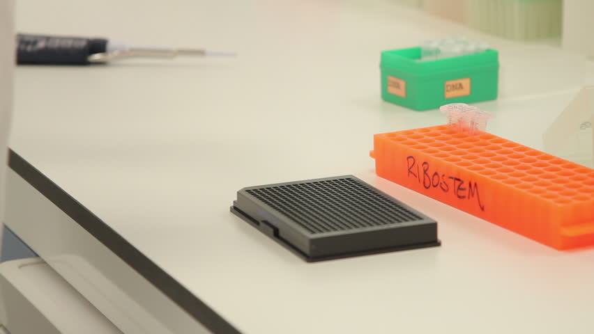 Scientist dropping liquid into vial in genetic laboratory