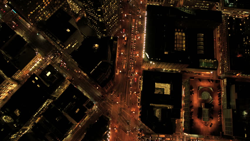 Aerial night vertical view of city street traffic and illuminated skyscrapers in an urban modern society