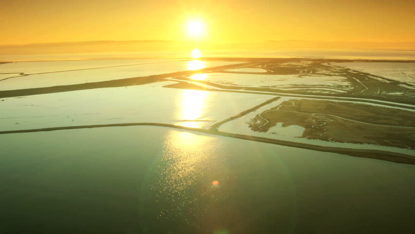 Aerial low angle view of natural mineral rich salt water ponds at sunset