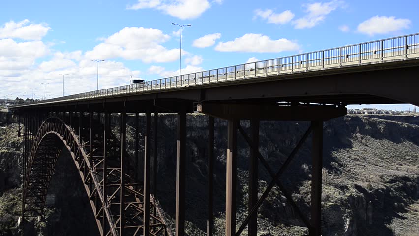 Vehicles, cars and trucks traveling over long bridge across canyon