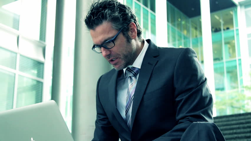 Business male working on laptop outside office