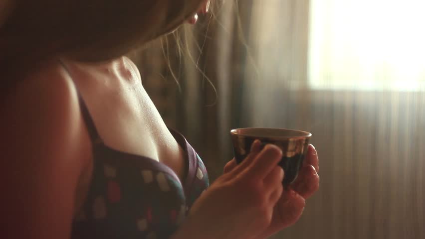 Молодая девушка пьет кофе обнаженная